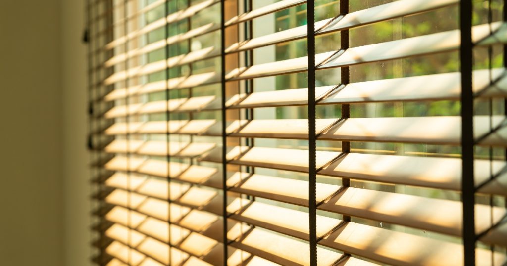 Wooden Blinds Partially Open, Allowing Sunlight To Filter Through The Slats